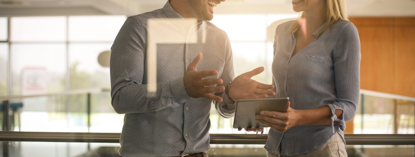 Business people standing in business building. Business woman showing something to her colleague on digital tablet. liderina - stock.adobe.com